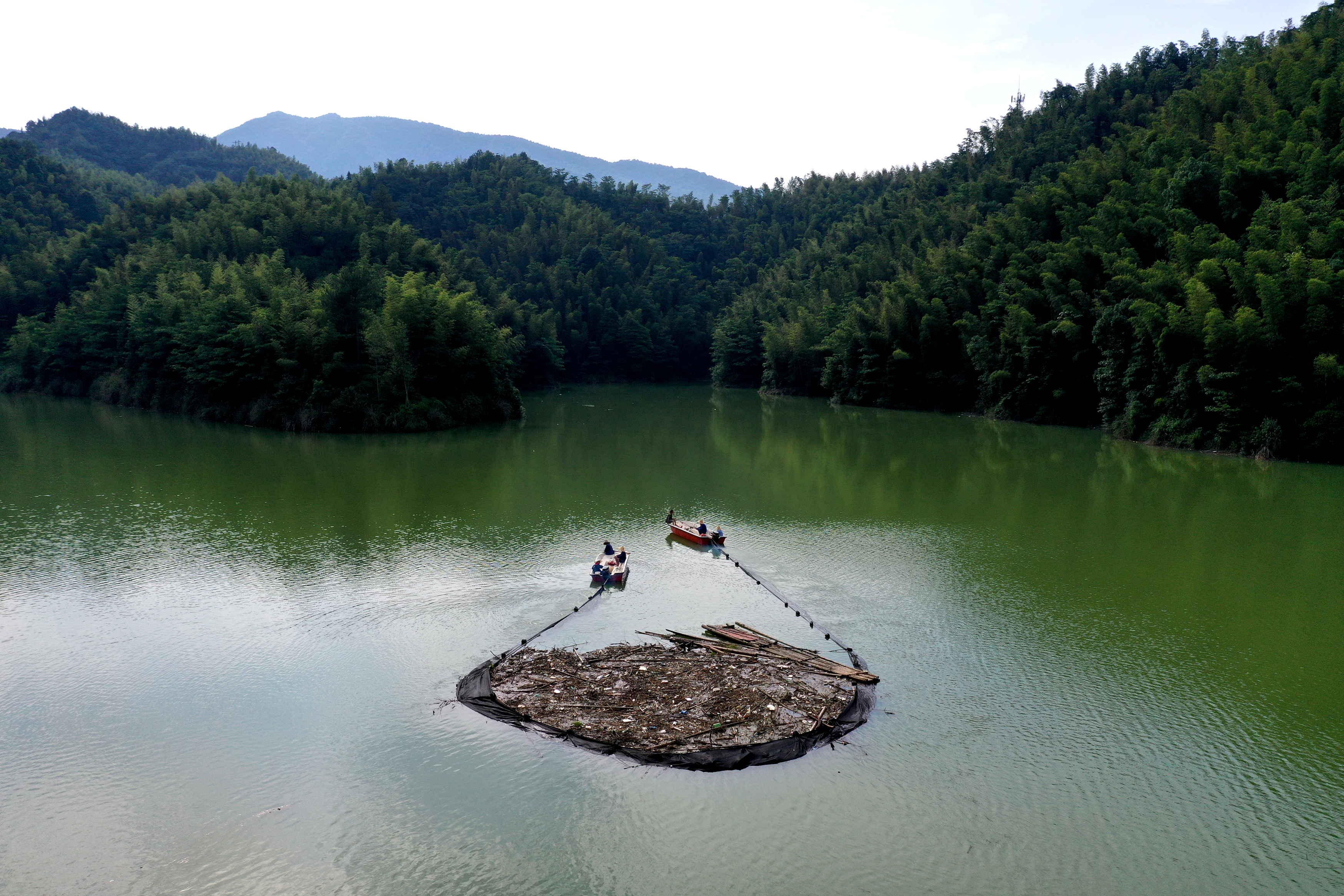 萍乡芦溪山口岩水库驾船拦网清理水面垃圾