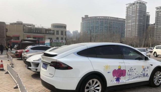 特斯拉车身被涂鸦，车主一脸无奈：打不得骂不得，她开心就好