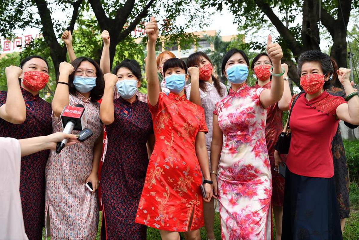 看看高考父母的穿搭：爸爸穿马褂，妈妈穿旗袍，手里还举着向日葵