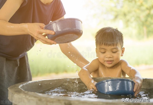 凝结盐花的中华香皂，挽着圆发髻的妇人在乡村的水井边给孩童洗澡