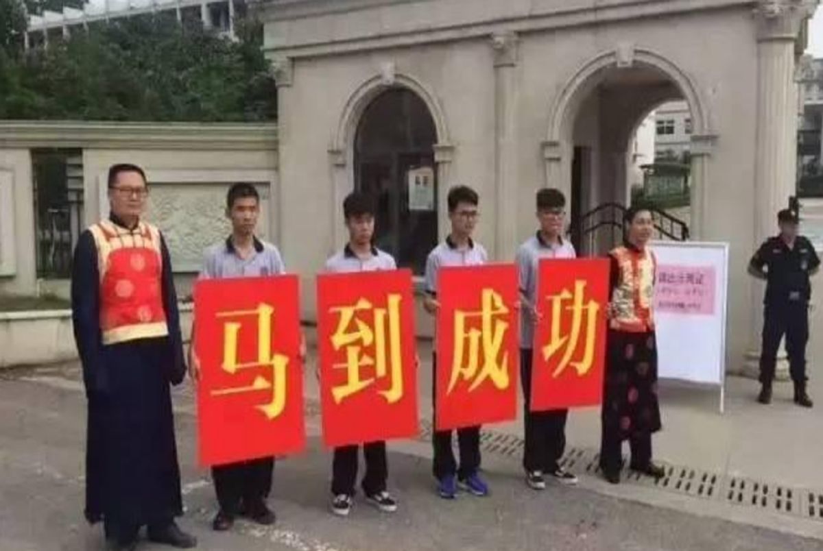 看看高考父母的穿搭：爸爸穿马褂，妈妈穿旗袍，手里还举着向日葵