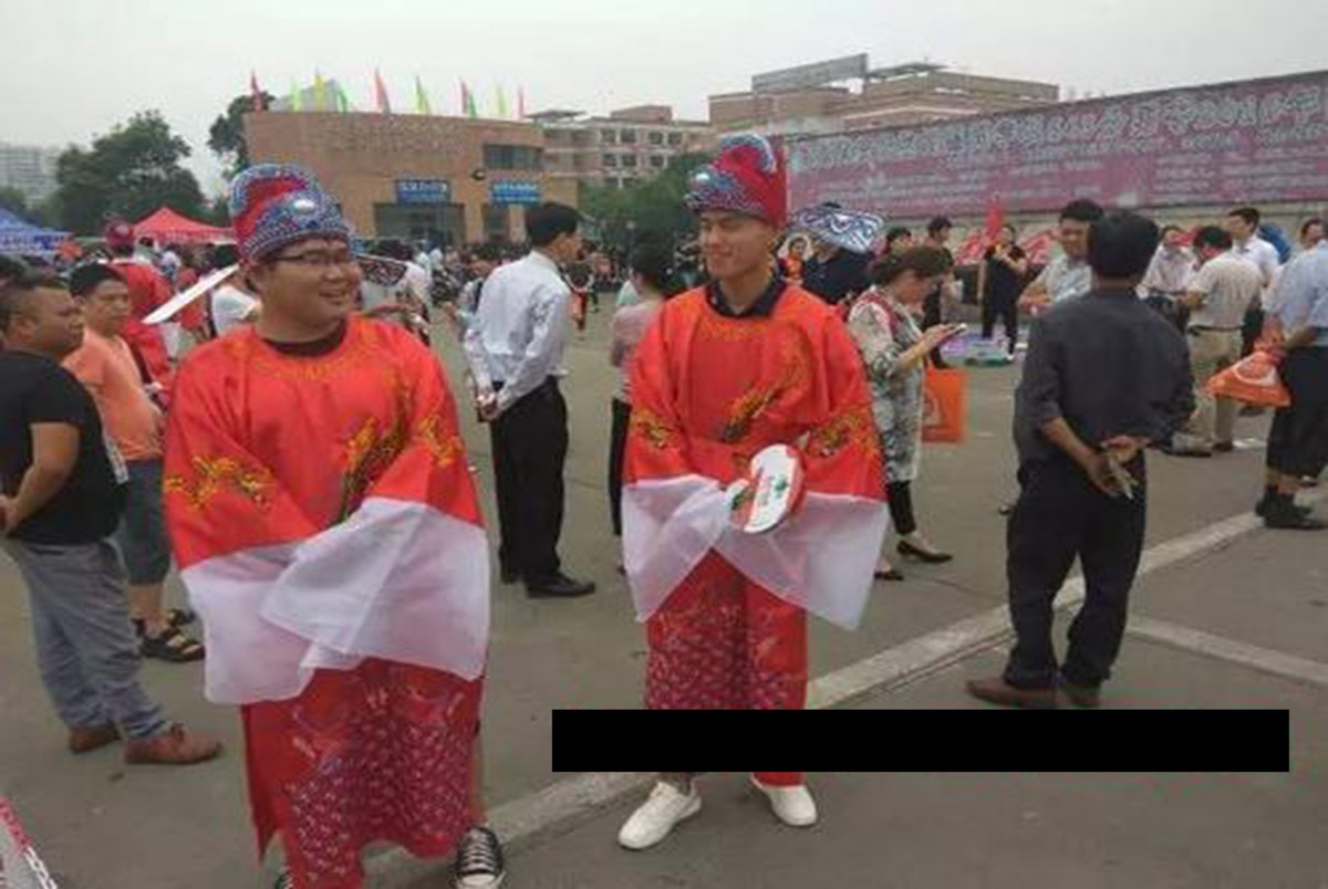 看看高考父母的穿搭：爸爸穿马褂，妈妈穿旗袍，手里还举着向日葵